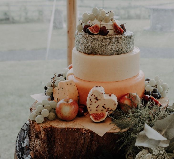 Three tier cheese wedding cake styled on rustic tree stump for relaxed country reception