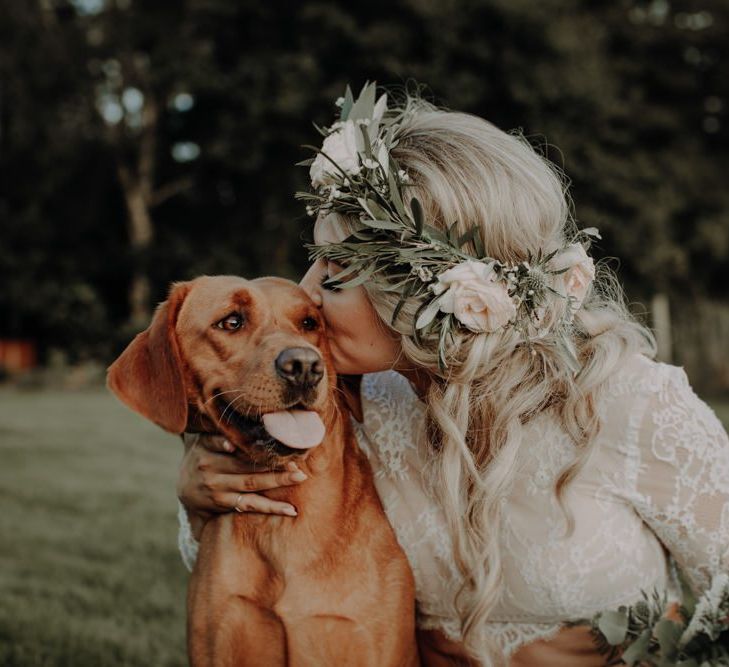 Bride wearing beautiful floral head piece enjoys a moment with her dog