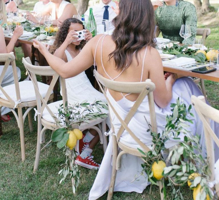 Bride Relaxes With Daughter and Guests With Strappy Bridal Gown and Lemon Wedding Decor