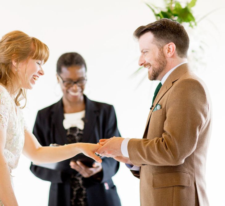 Bride in Jenny Packham Cassiopeia Wedding Dress with Groom in Brown Trousers and Blazer Exchanging Rings