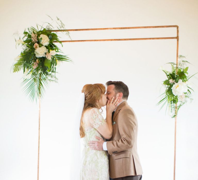 Bride in Jenny Packham Cassiopeia Wedding Dress with Groom in Brown Trousers and Blazer Kissing