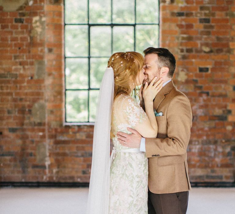 Bride in Jenny Packham Cassiopeia Wedding Dress with Groom in Brown Suit Kissing