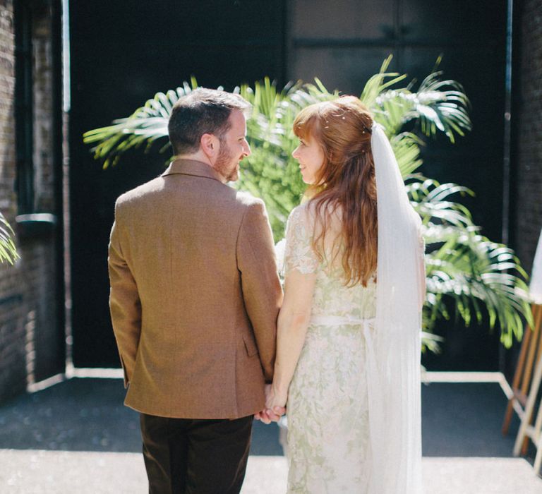 Bride in Jenny Packham Cassiopeia Wedding Dress with Groom in Brown Suit Holding Hands