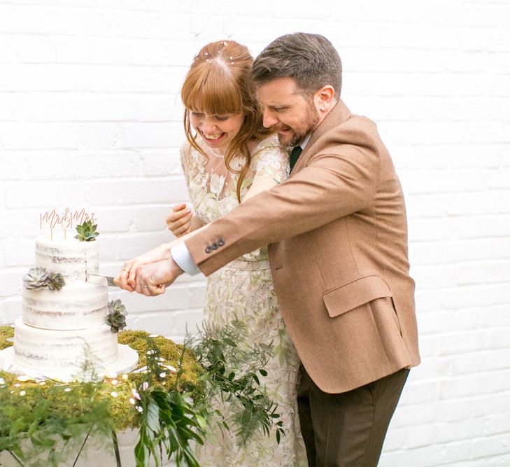 Bride and Groom Cutting the Semi Naked Wedding Cake on a Bed of Moss and Decorated with Succulents