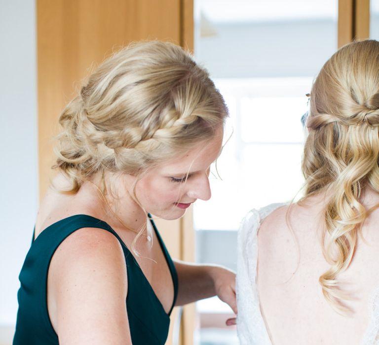 Bridesmaid with Side Braid Helping The Bride into Her Sassi Holford Wedding Dress