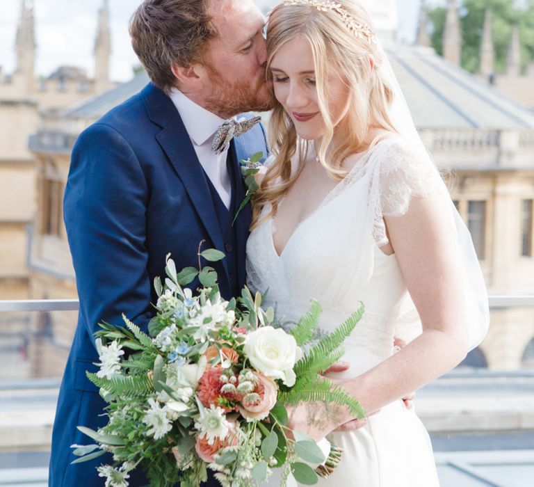 Groom in Navy Ted Baker Suit Kissing His Bride in Sassi Holford Tamara Wedding Dress