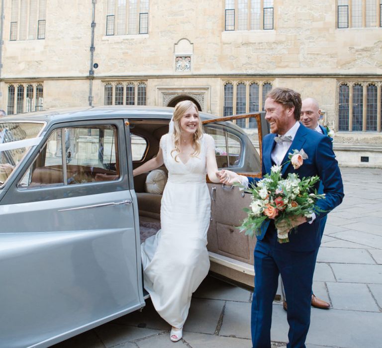 Groom in Navy Ted Baker Suit Helping His Bride in Sassi Holford Tamara Wedding Dress Out of The Wedding Car