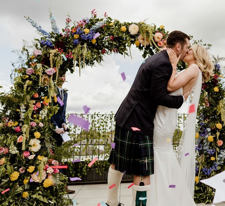 Groom wearing a kilt and bride and rooftop ceremony with multi-coloured confetti