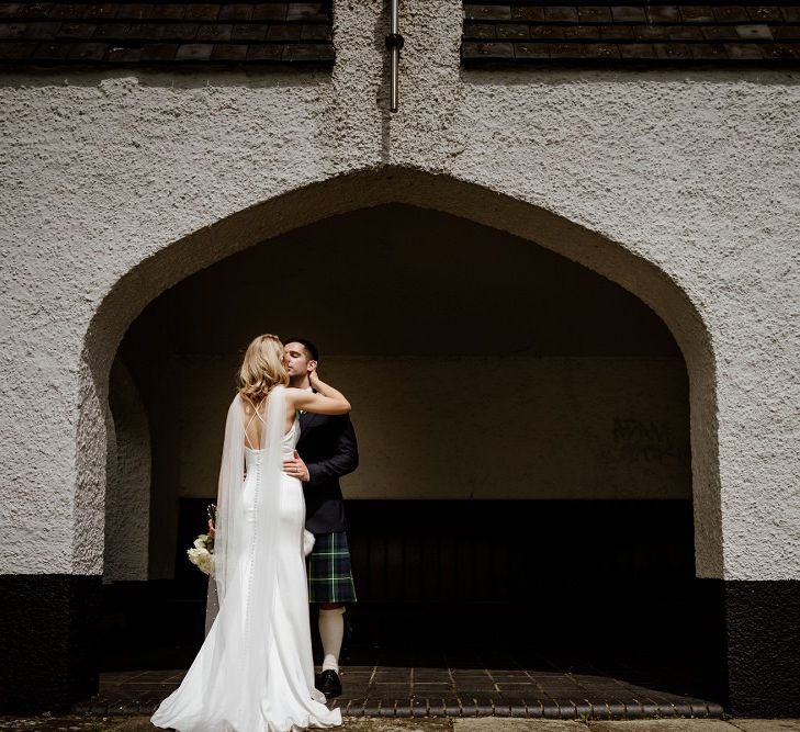 Bride and groom steal a moment wearing low back button detailed dress