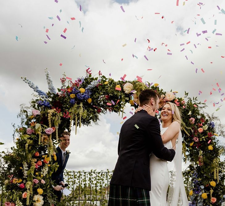 Multi-coloured floral moon gate for whimsical wedding with bright confetti