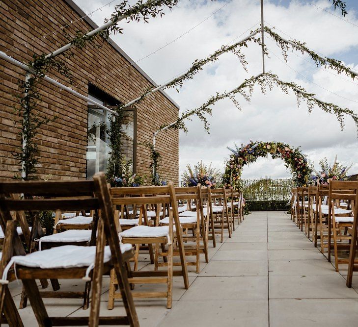 Outdoor wedding ceremony with floral moon gate and foliage decor