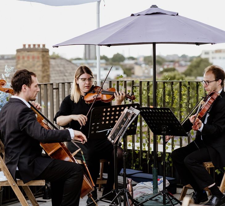 Wedding entertainment at outdoor rooftop celebration with the bride wearing a beautiful bridal jumpsuit