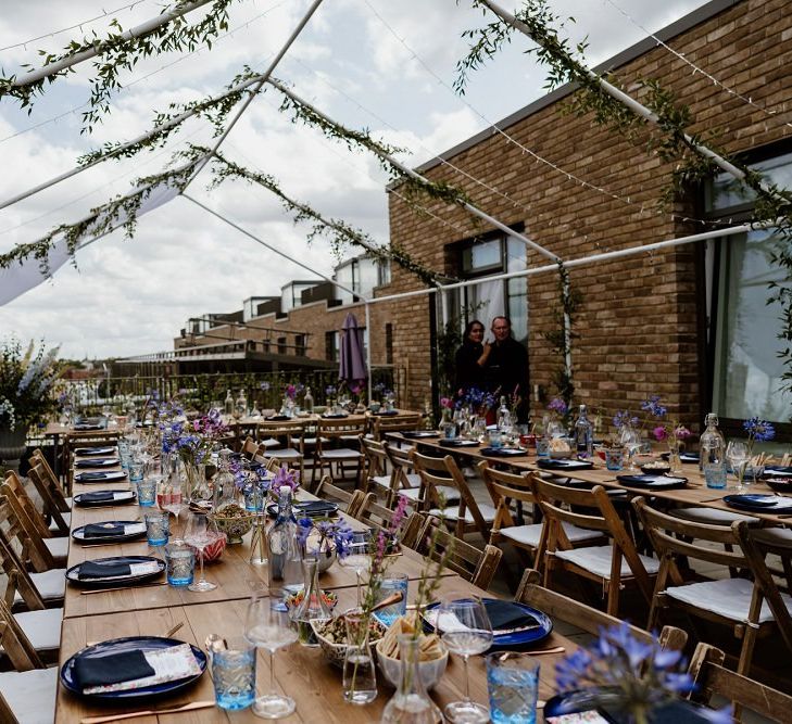 Private rooftop outdoor reception with floral decor and multi-coloured tableware