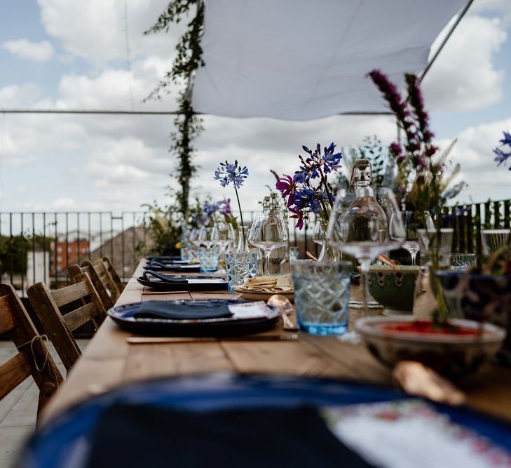 Outdoor rooftop reception in London wit floral table arrangements and a beautiful bridal jumpsuit