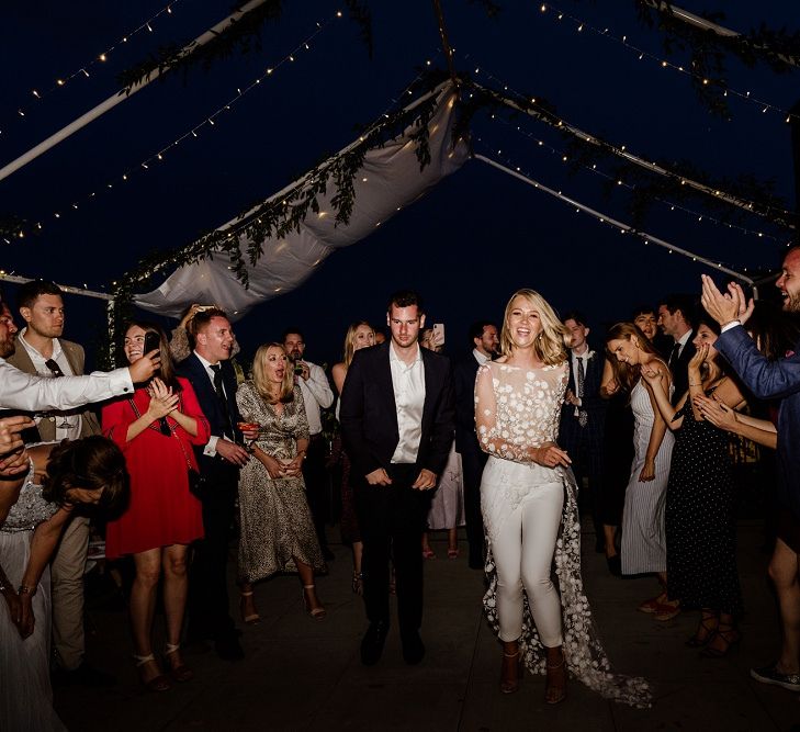 Bride wearing bridal jumpsuit at outdoor disco reception