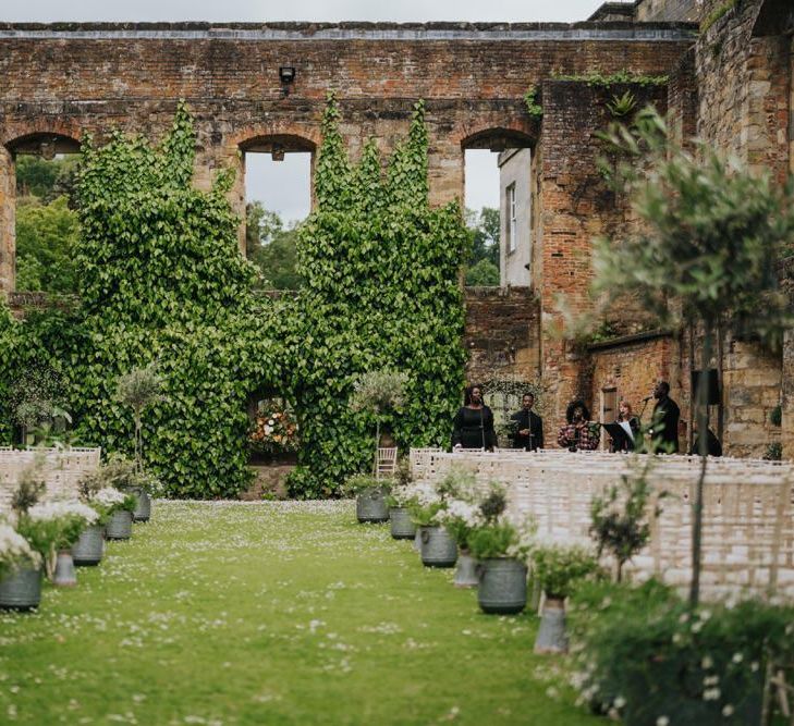 Outdoor wedding ceremony at Newburgh Priory with olive tree decor