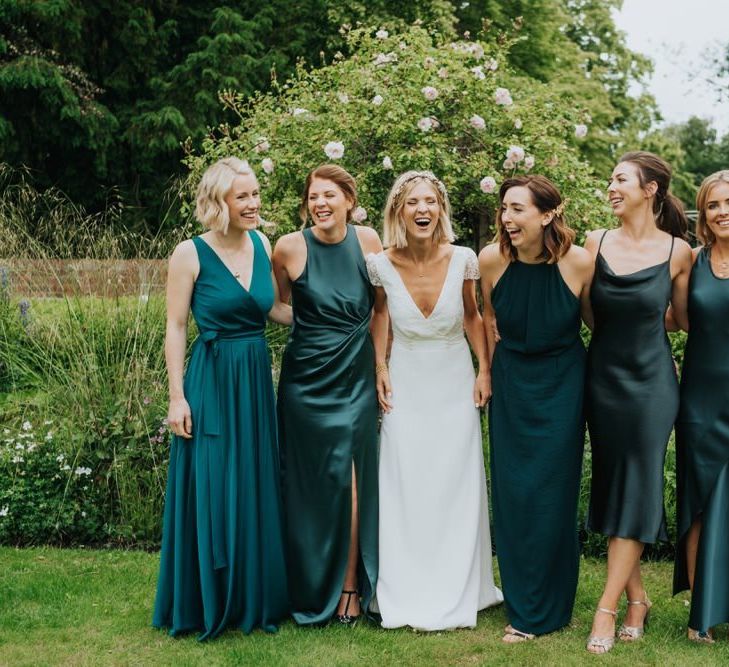 Bride and her bridesmaids in emerald green dresses for outdoor wedding ceremony