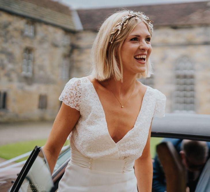 Bride arriving in a white vintage car at country house wedding with outdoor ceremony