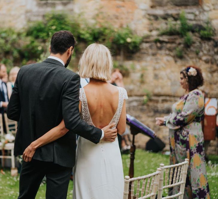 Bride and groom embrace at outdoor wedding ceremony with celebrant