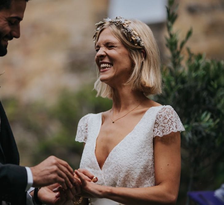 Bride wearing lace cap sleeved dress and gold embellished headband