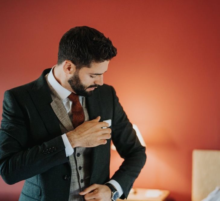 Groom getting ready wearing a three piece suit with a red tie