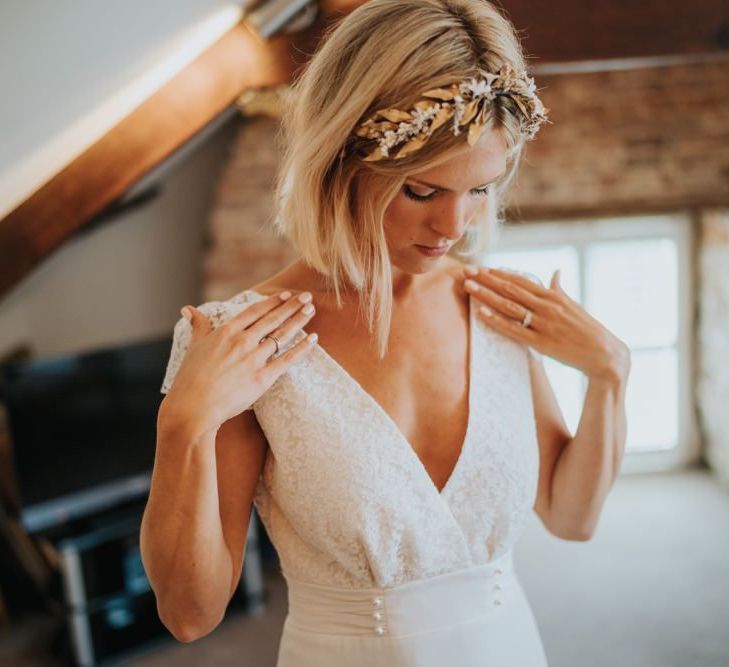 Bride wearing cap sleeve laced dress with pearl embellishment and a gold headband