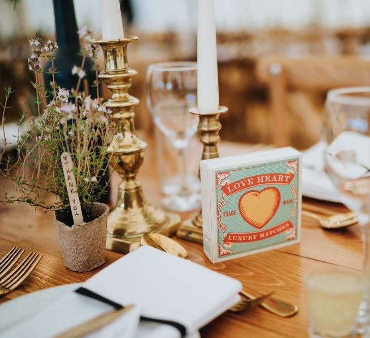 Gold candlesticks and painted wine bottle table numbers for marquee reception with rustic styling