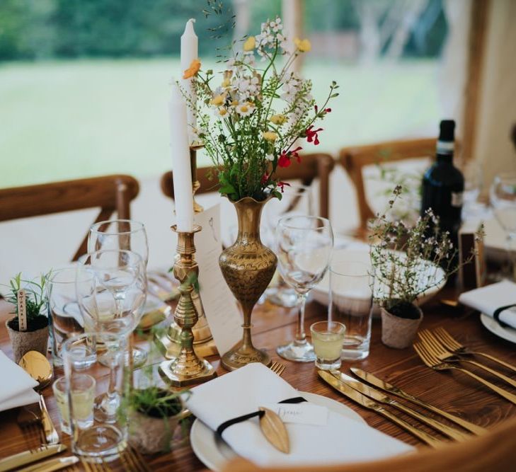 Gold candlesticks and foliage decor at marquee reception