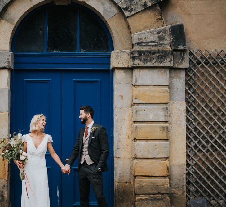 Bride wearing cap sleeve lace top dress and groom in three piece suit