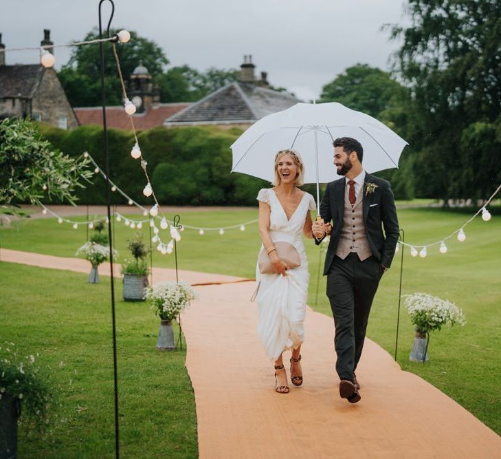 Bride and groom arrive at marquee reception with fairy lights