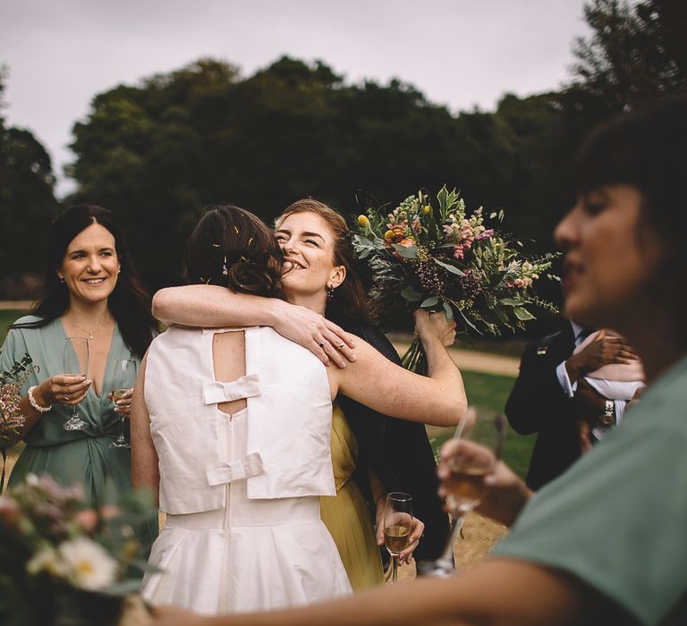 Bride in Homemade Wedding Dress with Bow Back Hugging Wedding Guests