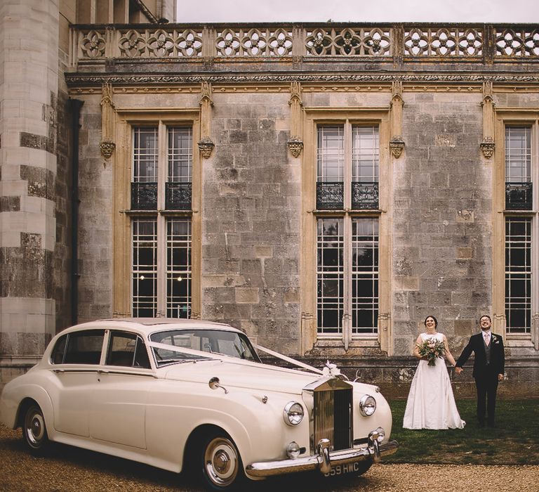 Bride and Groom Stnding in From top Their Castle Wedding Venue with Classic Wedding Car