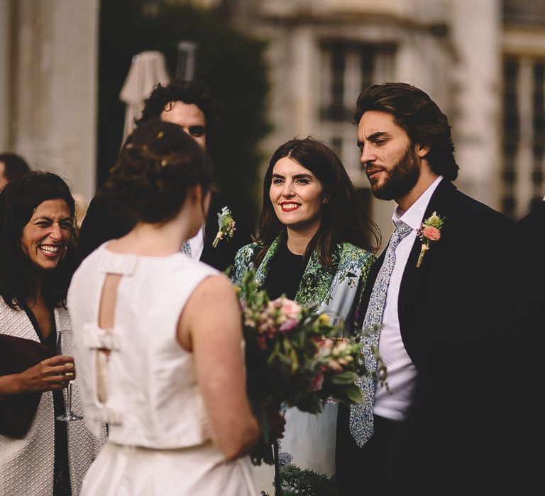 Bride in Homemade Wedding Dress with Bow Back Detail Talking to Wedding Guests