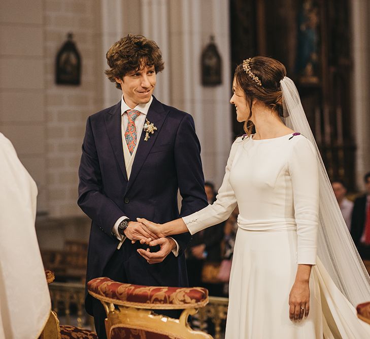 Church Wedding Ceremony with Bride in Nnavascues Embroidered Back Wedding Dress and Groom in Navy Suit Holding Hands at the  Altar