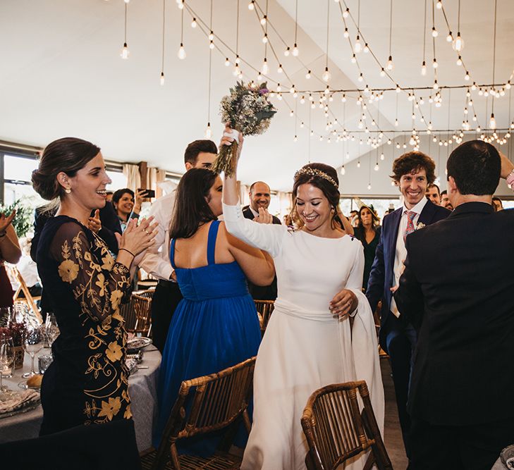 Bride in Nnavascues Embroidered Back Wedding Dress and Groom in Navy Suit Entering The Wedding Reception