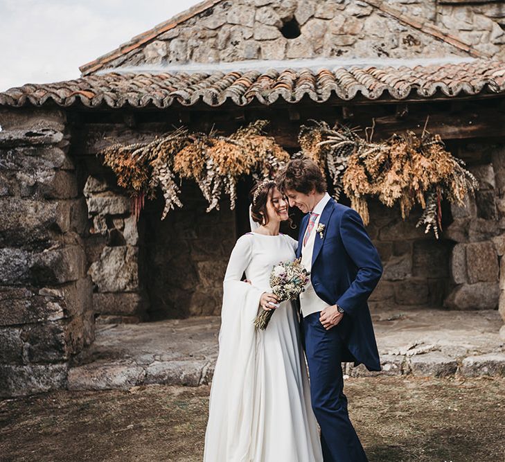 Bride in Nnavascues Embroidered Back Wedding Dress and Groom in Navy Suit