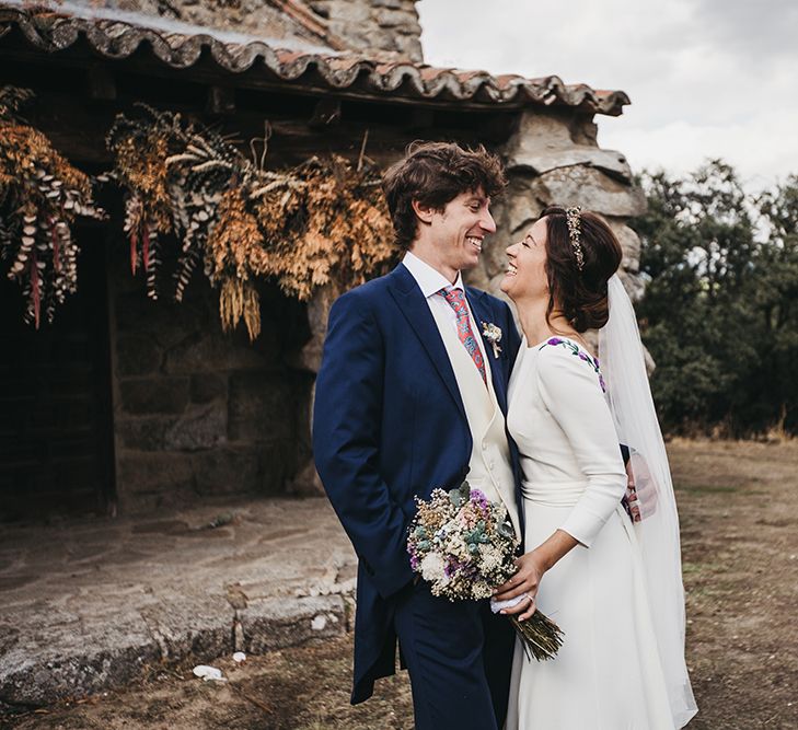 Bride in Nnavascues Embroidered Back Wedding Dress and Groom in Navy Suit