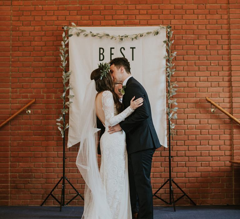 Church Wedding Ceremony with Bride and Groom Kissing in Front of a Best Day Ever Banner