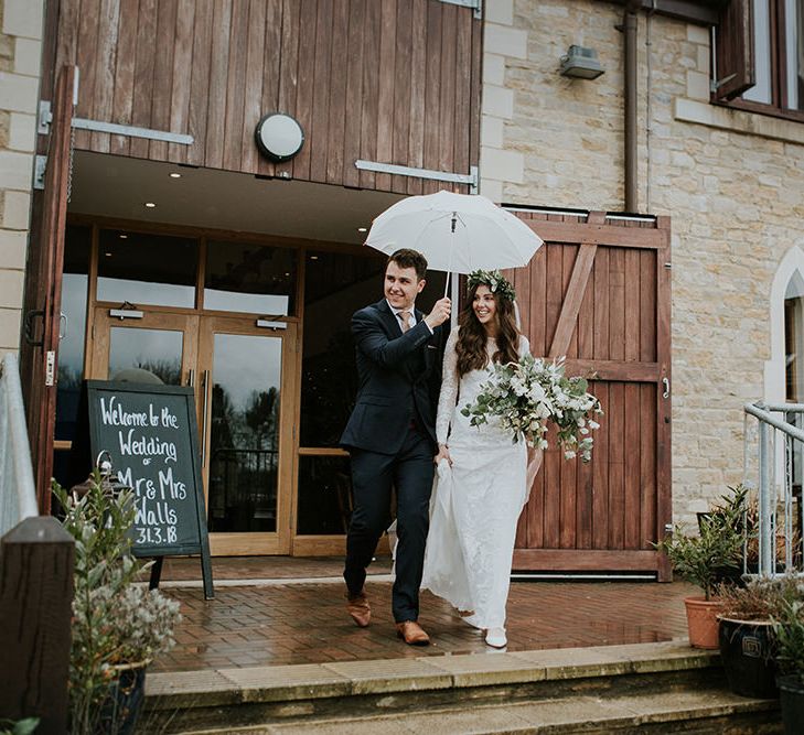 Bride and Groom Exiting The Wedding Venue Under an Umbrella