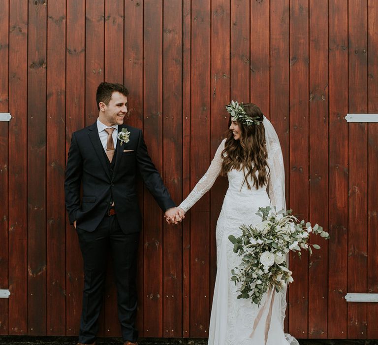 Bride Long Sleeve Grace Loves Lace Wedding Dress and Groom in Moss Bros. Suit Holding Hands