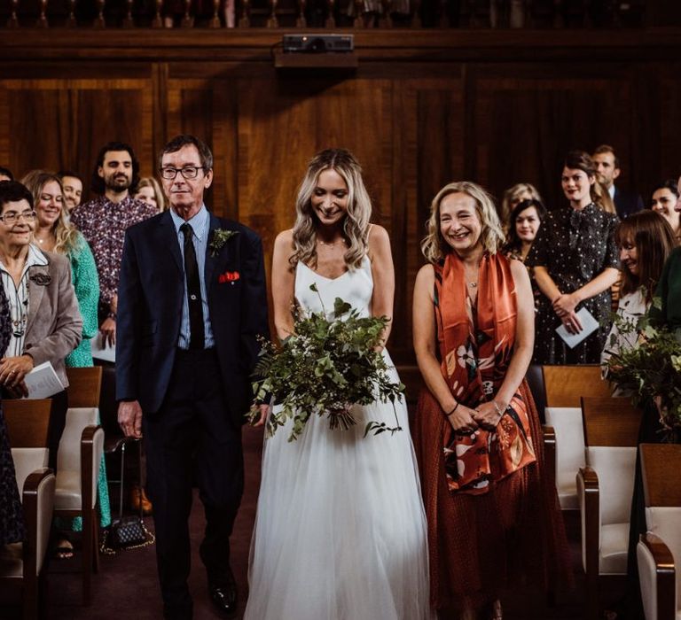 Bride walking down the aisle at Stoke Newington Town Hall wearing two piece gown and foliage bouquet