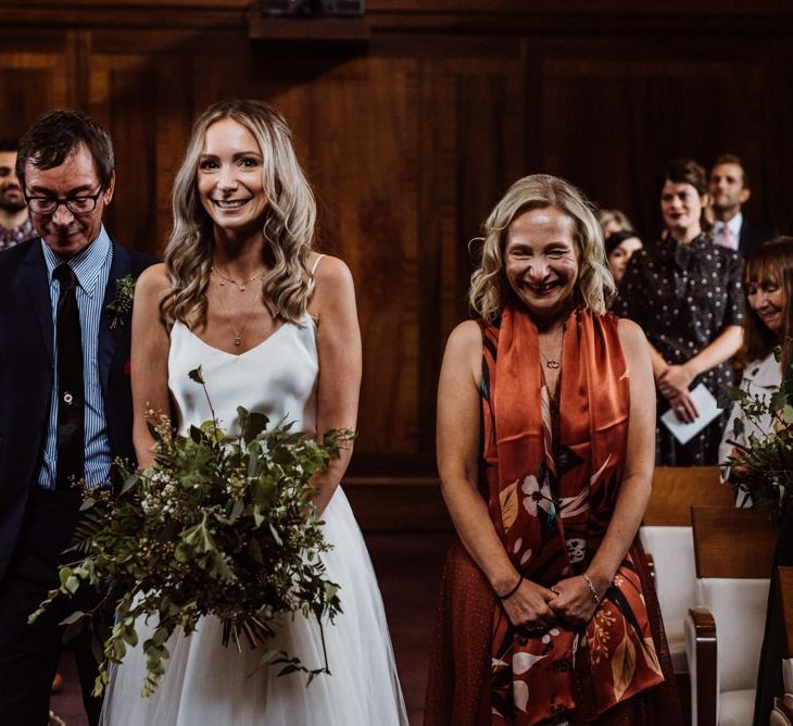 Bride walking down the aisle at Stoke Newington Town Hall wearing two piece gown and foliage bouquet