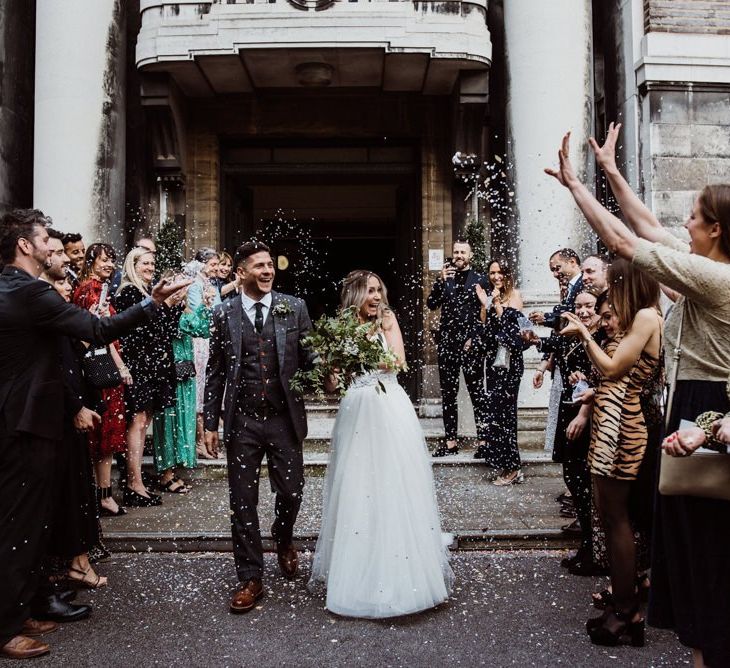 Confetti shot as couple exit Stoke Newington Town Hall with foliage bouquet