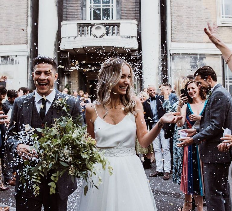 Confetti shot as couple exit Stoke Newington Town Hall with foliage bouquet