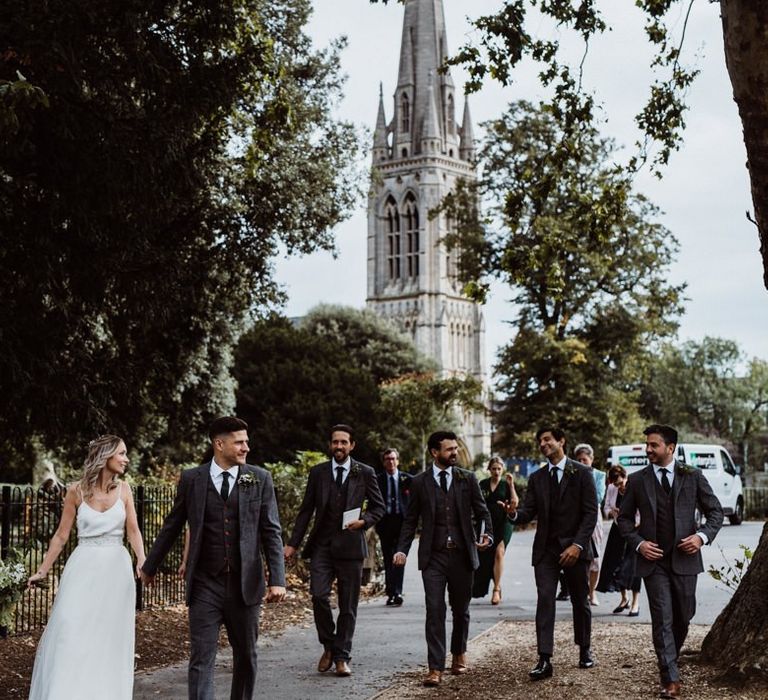 Bride and groom walk with their guests to their reception