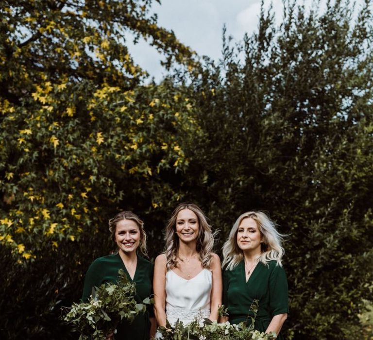 Bride and bridesmaids wearing emerald green dresses and foliage bouquets