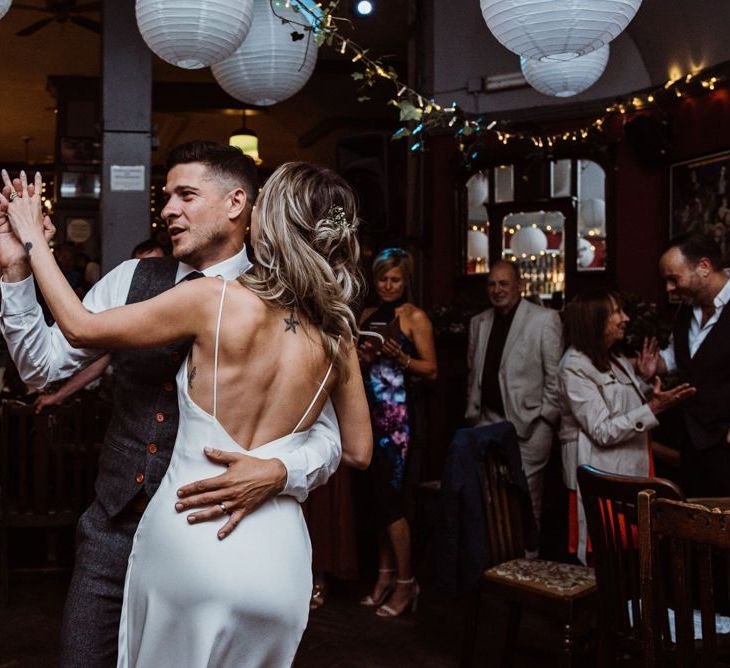 Bride and grooms first dance at pub reception with hanging foliage decor