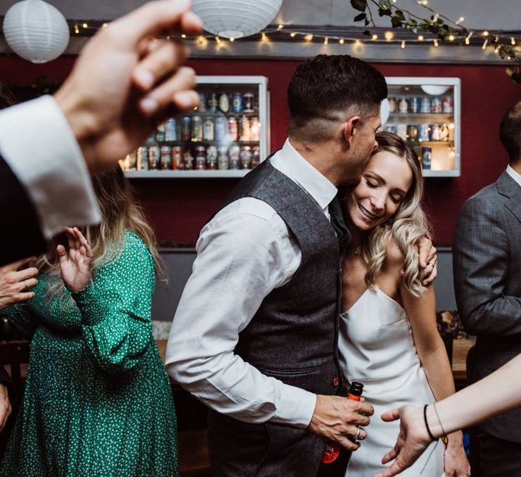 Bride and grooms first dance at pub reception with hanging foliage decor