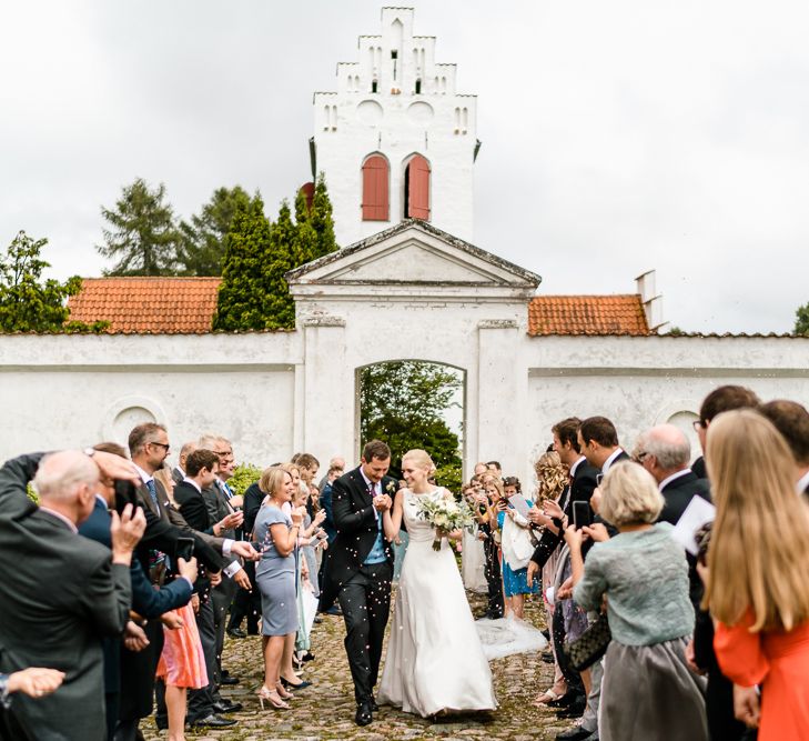 Confetti Exit | Bride in Caroline Castigliano Wedding Dress | Groom in Henry Herbert Tailors Morning Suit | Traditional Green/Blue Danish Wedding at Scandinavian Country House, Jomfruens Egede in Faxe, Denmark | John Barwood Photography