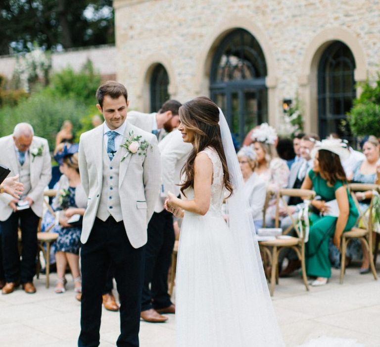 Bride in Catherine Deane Wedding Dress and Groom in Beige Blazer Exchange Vows